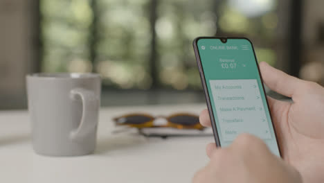 Sliding-Shot-Approaching-a-Hand-Holding-a-Smartphone-On-a-Mobile-Banking-App