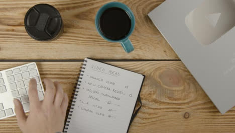 Top-Down-Shot-of-a-Content-Creator-at-Rustic-Desk-Typing-On-Computer-Keyboard