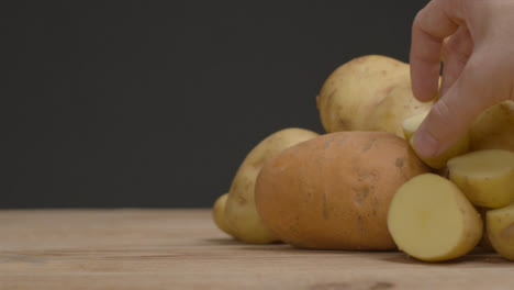 Nahaufnahme-Eines-Haufens-Von-Verschiedenen-Kartoffeln-Als-Hand-Nimmt-Zwei-Weg