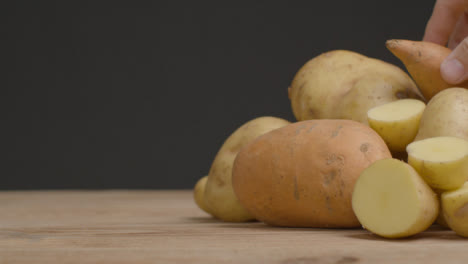 Nahaufnahme-Von-Verschiedenen-Kartoffeln-Als-Hand-Legt-Zwei-Auf-Stapel