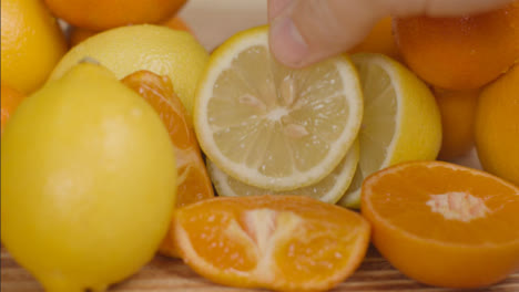 Close-Up-Shot-of-Hand-Placing-Lemon-Slice-On-Pile-of-Citrus-Fruit