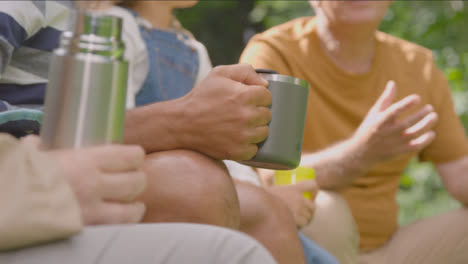 Pull-Focus-Shot-of-People-Holding-Drinks-On-Camping-Trip-01