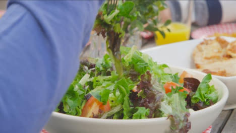 Fotografía-Por-Encima-Del-Hombro-De-Una-Mujer-Sirviéndose-Ensalada