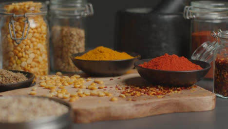 Sliding-Shot-of-Spices-and-Grains-on-Black-Worktop