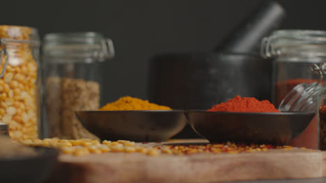 Tracking-In-Shot-of-Spices-and-Grains-on-Black-Worktop