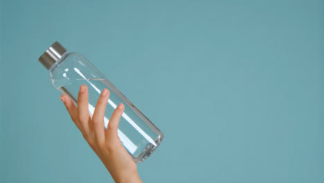 Nahaufnahme-Der-Hand-Der-Jungen-Frau,-Die-Wasserflasche-In-Den-Rahmen-Mit-Kopienraum-01-Bringt