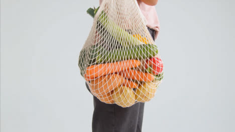 Side-Profile-Shot-of-Young-Adult-Woman-Holding-Bag-of-Vegetables