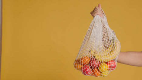 Medium-Shot-of-Young-Adult-Womans-Hand-Holding-Up-Bag-of-Fruit