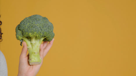 Close-Up-Shot-of-Young-Adult-Woman-Holding-Broccoli