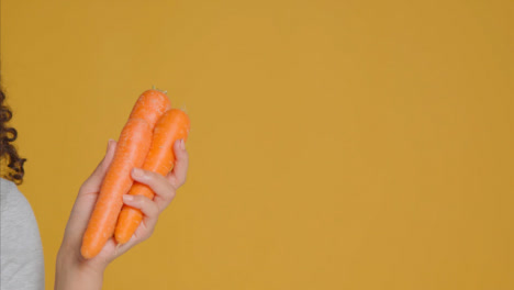 Primer-Plano-De-Una-Mujer-Adulta-Joven-Sosteniendo-Zanahorias