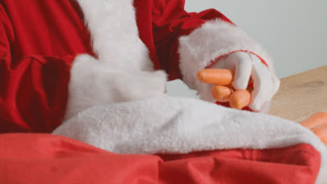 Close-Up-Shot-of-Santa-Pulling-Carrots-Out-from-Red-Sack