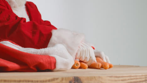 Close-Up-Shot-of-Santa-Pulling-Carrots-Out-from-a-Red-Sack