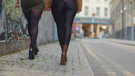 Low-Angle-Shot-of-Two-Young-Women-Walking-Down-English-Street
