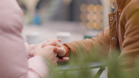 Close-Up-Shot-of-Two-Young-Women-Holding-Hands-at-Outdoor-Table