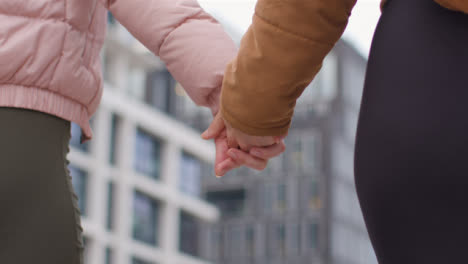 Low-Angle-Shot-of-Two-Woman-Holding-Hands-as-They-Walk-Together