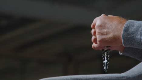 Low-Angle-Shot-of-Senior-Mans-Hands-Holding-Rosary-Beads