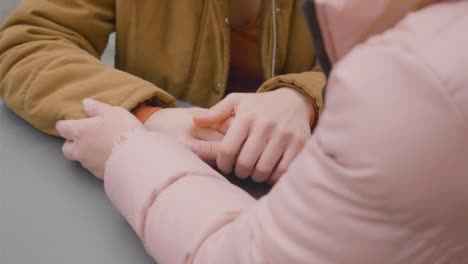 Close-Up-of-Two-Women-Holding-Hands-at-Outdoor-Table
