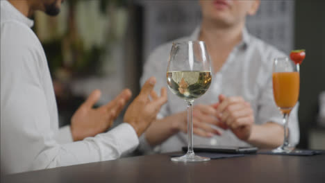 Nahaufnahme-Von-Einem-Glas-Wein-Auf-Dem-Tisch,-Während-Männer-Im-Hintergrund-Sprechen