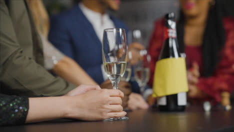 Close-Up-Shot-of-Glass-of-Champagne-On-Table-as-Friends-In-Background-Celebrate-New-Years