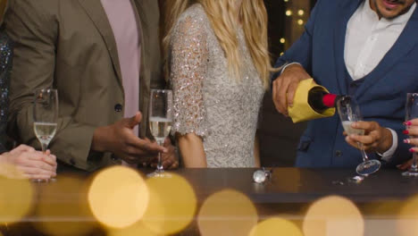 Mid-Section-Friends-Pouring-Champagne-During-New-Years-Celebrations