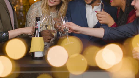 Mid-Section-Friends-Toasting-Champagne-During-New-Years-Celebrations-In-a-Bar