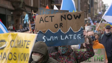 Handheld-Shot-of-'Act-Now-or-Swim-Later'-Sign-During-Climate-Change-Protests-In-Glasgow