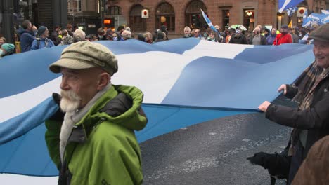 Handheld-Shot-of-Climate-Change-Protesters-Marching-Through-Glasgow-with-Giant-Scottish-Flag