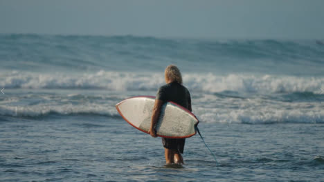 Totale-Aufnahme-Eines-Surfers,-Der-Auf-Bali-Ins-Meer-Geht