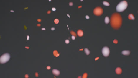 Stationary-Shot-of-Coloured-Confetti-Falling-Against-a-Grey-Background