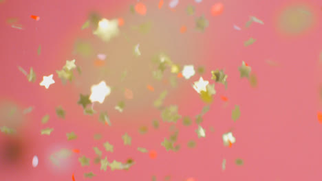 Stationary-Shot-of-Coloured-and-Gold-Confetti-Falling-Against-a-Pink-Background