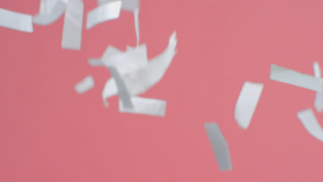 Stationary-Shot-of-Silver-Confetti-Falling-Against-Pink-Background