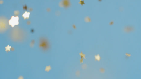 Stationary-Shot-of-Gold-Confetti-Falling-Against-a-Blue-Background