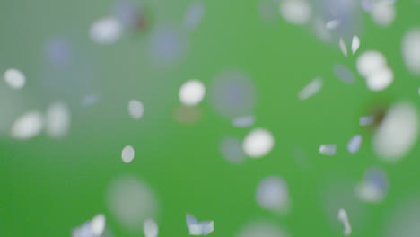 Stationary-Shot-of-Blue-and-Gold-Confetti-Falling-Against-Green-Background