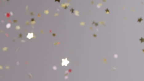 Stationary-Shot-of-Gold-and-Pink-Confetti-Falling-Against-Grey-Background