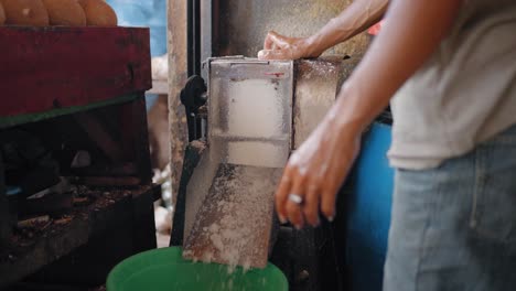 Tracking-Shot-Approaching-Young-Man-Using-Machine-to-Shave-Coconuts