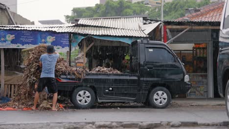 Toma-Amplia-De-Trabajadores-Descargando-Plátanos-De-Una-Furgoneta-Bajo-La-Lluvia