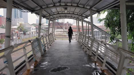 Tracking-Shot-Following-Woman-Walking-Across-Jakarta-Footbridge-