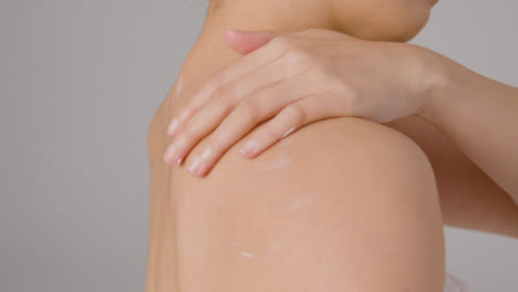 Close-Up-Shot-of-Young-Woman-Blending-Cream-into-Back