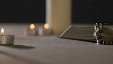 Tracking-Shot-of-Candles-Lit-around-a-Bible-and-Crucifix