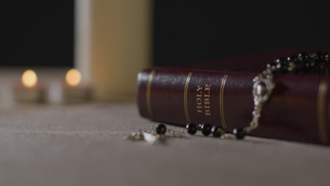 Tracking-Shot-of-Candles-Lit-around-a-Bible-and-a-Crucifix
