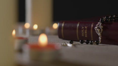 Tracking-Shot-of-Candles-Lit-around-Bible-and-a-Crucifix