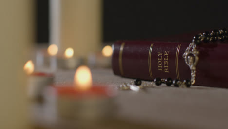 Tracking-Shot-of-Candles-Lit-around-Holy-Bible-and-Crucifix