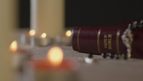 Tracking-Shot-of-Candles-Lit-around-a-Holy-Bible-and-Crucifix