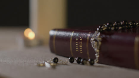 Tracking-Shot-of-Candles-Lit-around-a-Holy-Bible-and-a-Crucifix