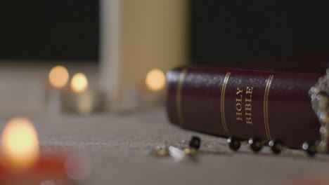 Tracking-Shot-of-Candles-Lit-around-Holy-Bible-and-a-Crucifix