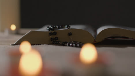 Tracking-Shot-of-Burning-Candles-Around-a-Holy-Bible-and-a-Crucifix