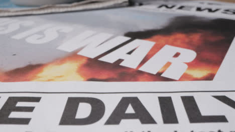 Tracking-Close-Up-of-Various-Newspaper-Headline-This-Is-War