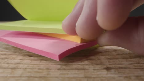 Close-Up-of-Someone-Taking-Sticky-Note-from-Pile