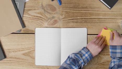 Overhead-Shot-of-a-Man-Writing-on-Sticky-Note