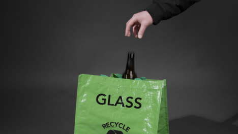 Mittlere-Aufnahme-Einer-Glasflasche,-Die-In-Einen-Recyclingbeutel-Gelegt-Wird